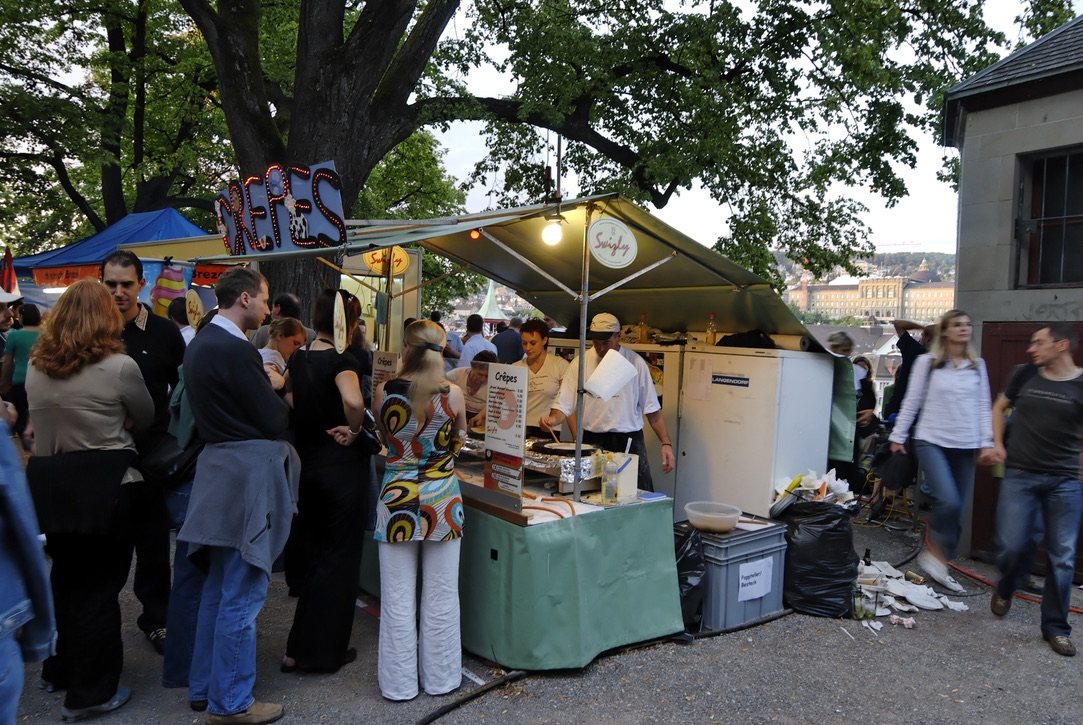Belebter Crêpes-Stand am Abend, Gäste warten vor dem Stand